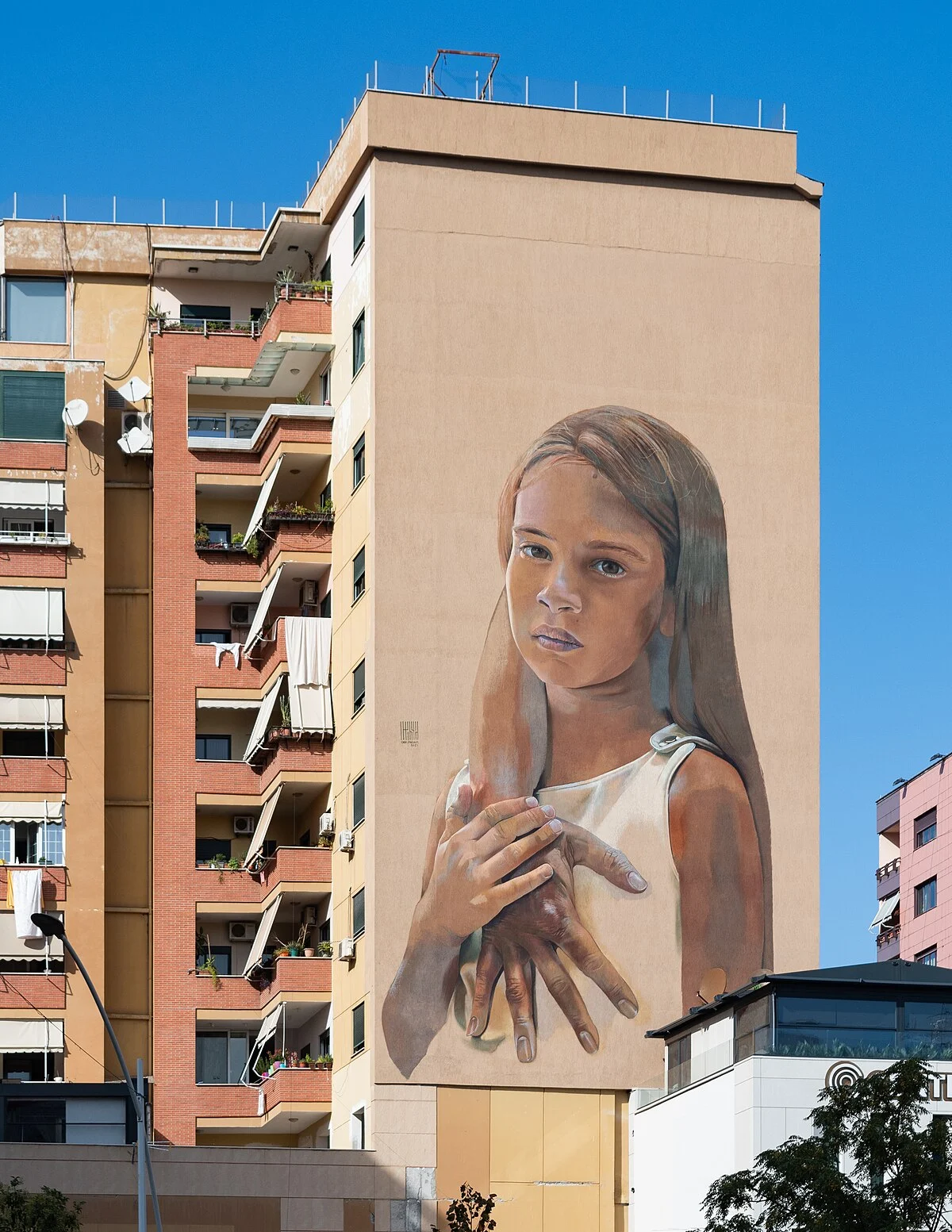 Wandbild „Mother's Care“ des deutschen Künstlers Case Maclaim, gestaltet 2021 im Rahmen des „Tirana Mural Fest“, an einer Hochhausfassade…