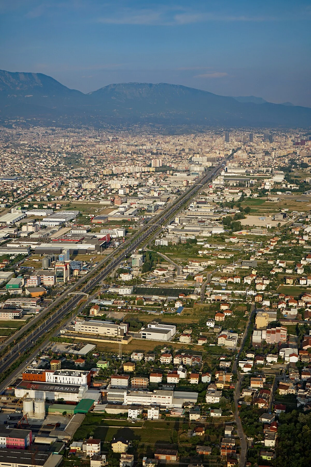 Kashar am westlichen Stadtrand von Tirana aus der Luft mit der SH2 Autobahn Durrës–Tirana, Hochhäuser des Stadtzentrums in der…